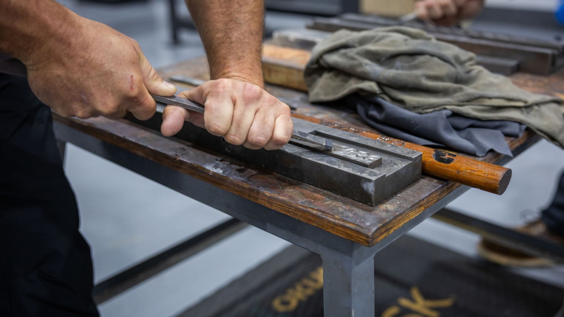 a technician hand scraping precision components as part of preventative maintenance cleaning to remove buildup and maintain machine performance.