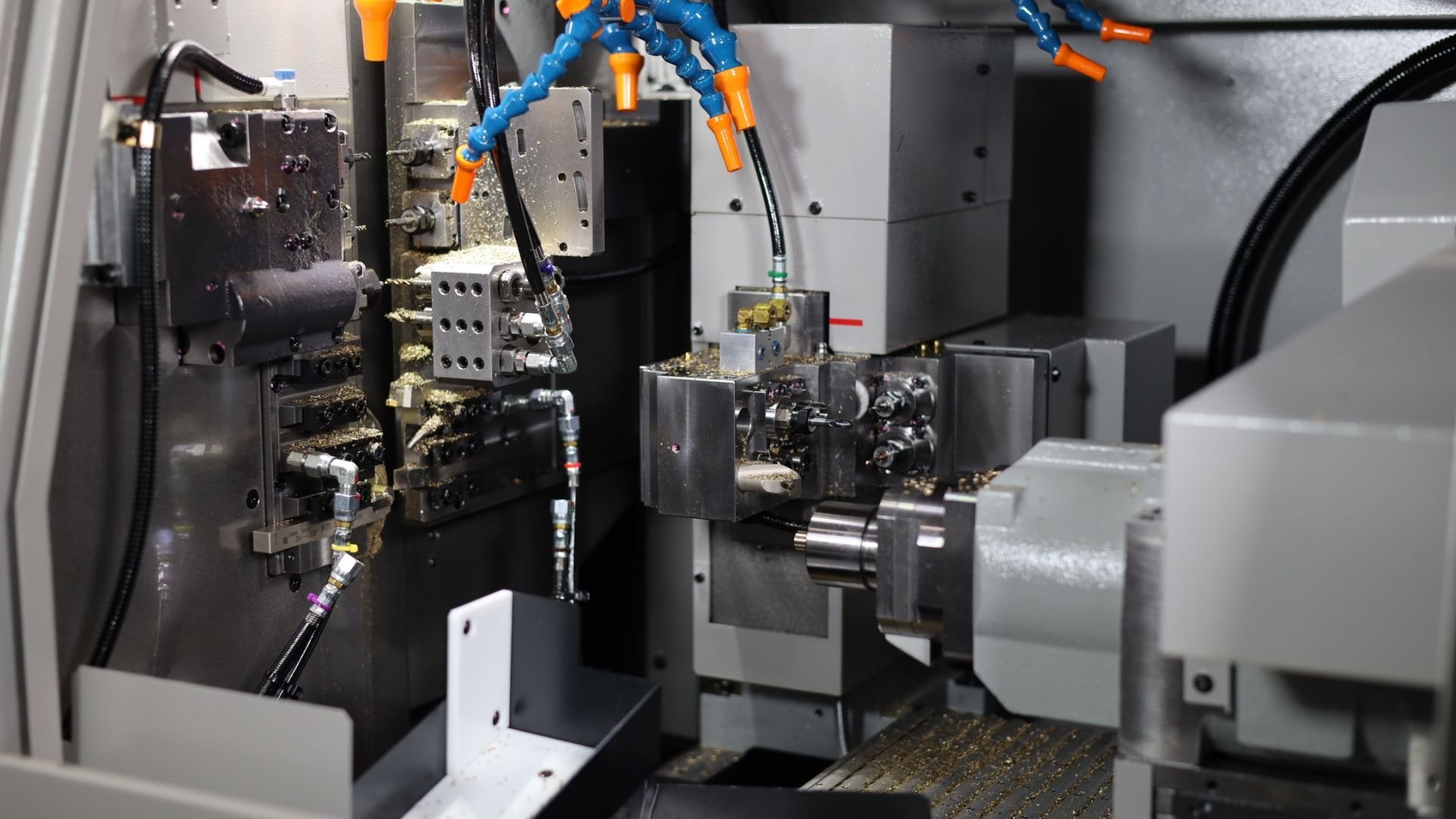 Interior view of a Tsugami Swiss-type lathe showing tooling, coolant lines, spindle area and an integrated parts tray inside the machine enclosure.